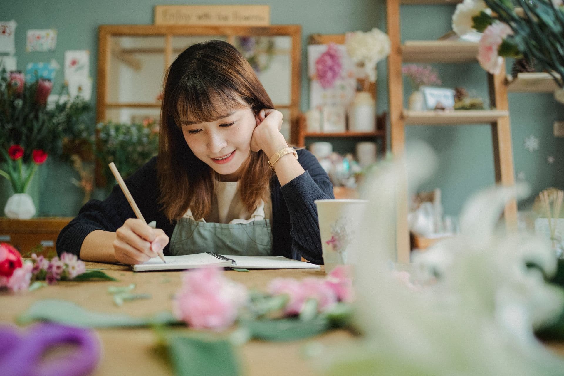 Dueña de una floristería anotando tareas en su libreta dentro del local